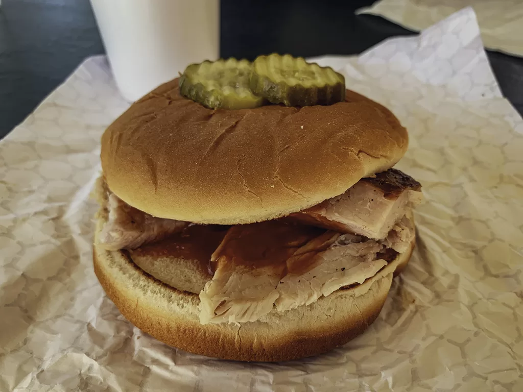 A smoked turkey sandwich with pickles on top.